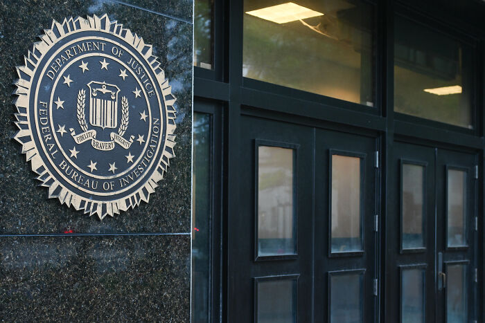 FBI seal mounted on building wall next to closed dark doors, highlighting legal right questions in Texas redistricting case.