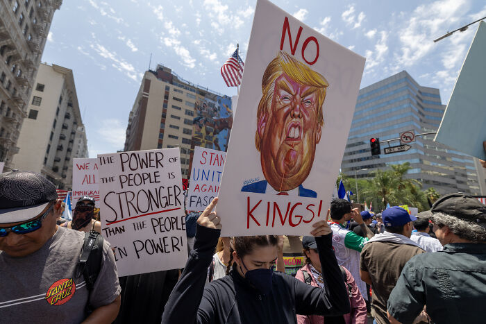 Protesters holding signs against Trump and discussing power during a Library of Congress webpage removal controversy.