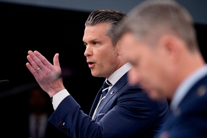 Man in a suit speaking at a podium about U.S. Air Force blocking retirement pay for transgender service members.