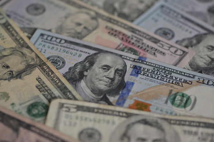 Close-up of various U.S. dollar bills representing the rising U.S. national debt and economic impact of tariffs.