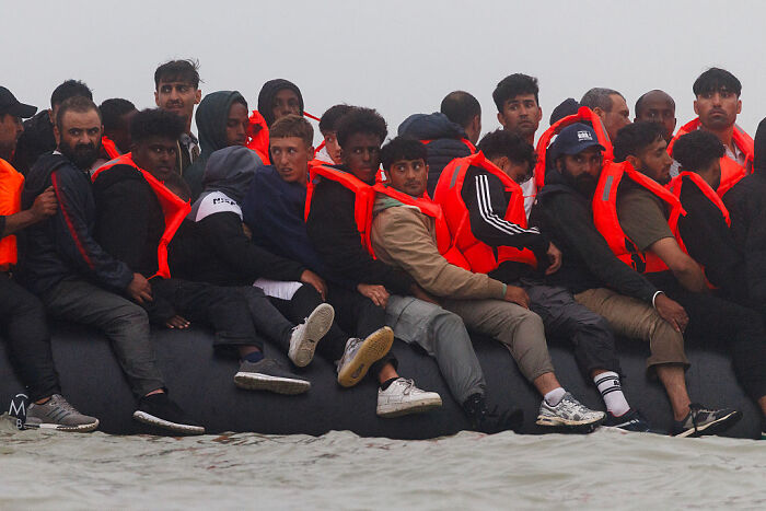 Group of men wearing life jackets on a small boat amid a tense situation with French cops during UK-bound boarding attempt