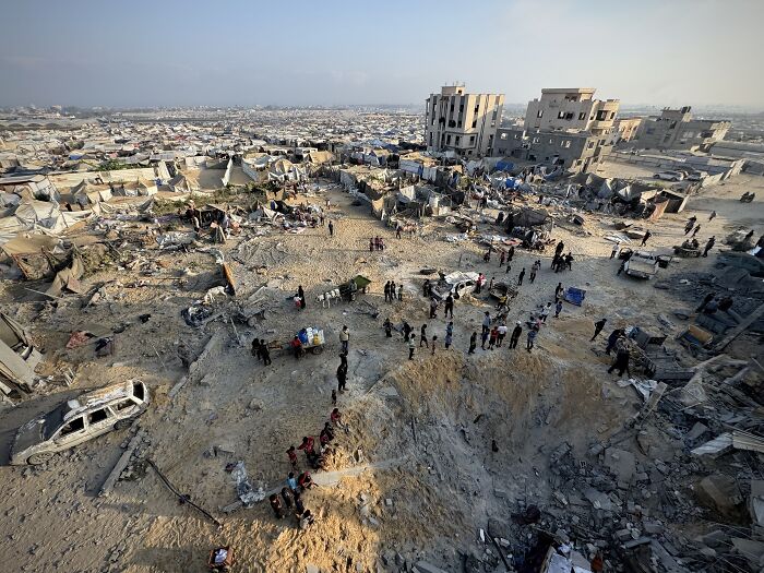 Aerial view of destroyed buildings and people gathering in rubble, highlighting major countries recognizing Palestine.