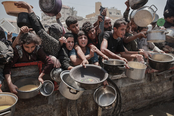 Group of people in Palestine holding empty pots and pans, highlighting why major countries are recognizing Palestine.