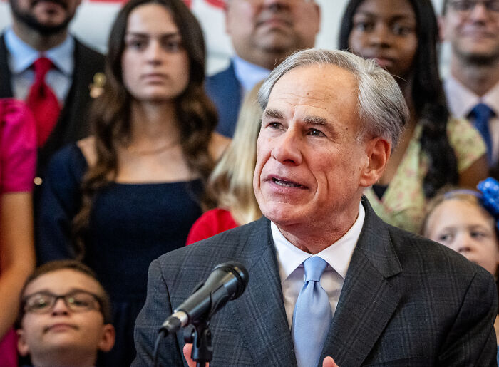 Texas governor speaking at a podium during a press event about GOP redistricting and potential map overhaul efforts.