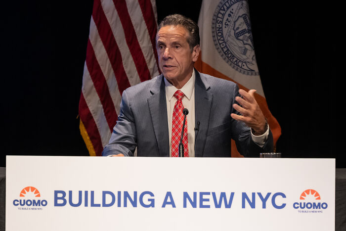 Eric Adams speaking at a podium with NYC flags, addressing issues including adult work decriminalization in New York.