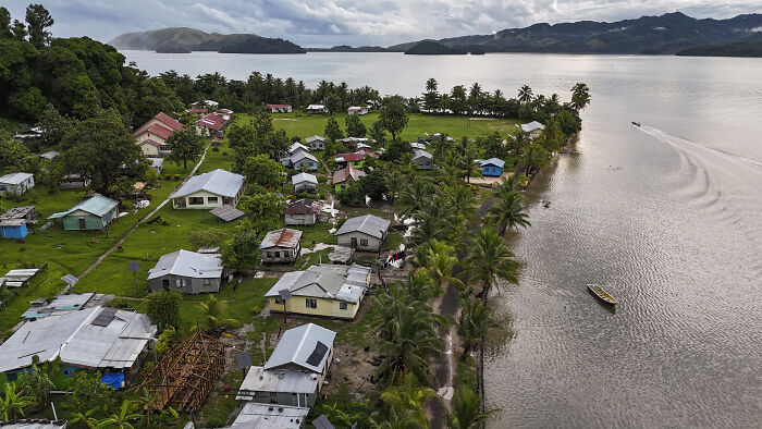 A coastal village in the Pacific Islands with homes near water, illustrating climate-driven dengue fever health risks.