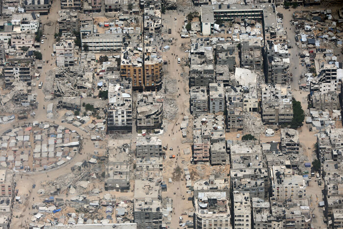 Aerial view of destroyed buildings in a conflict zone highlighting dangers faced by journalists amid global press freedom decline.