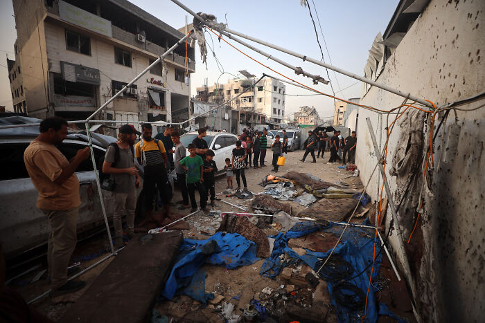 Damaged street and wreckage with people gathered, illustrating the impact on journalists amid Israel press freedom crisis.