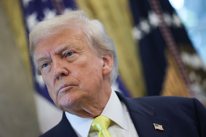 Close-up of Donald Trump in a suit with U.S. flag pin, highlighting themes of altered human rights report and U.S. priorities.