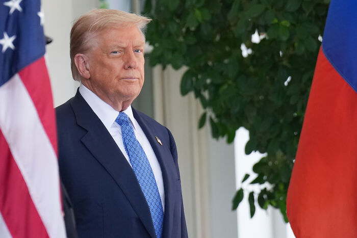 Donald Trump standing near flags at the White House, related to moving Barack Obama portrait to a concealed location.