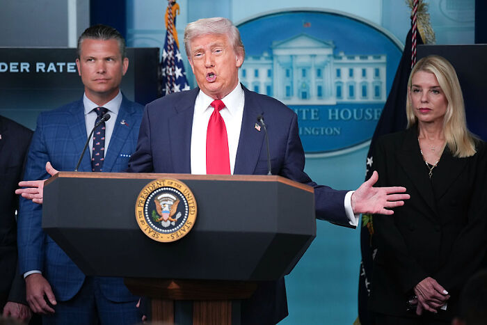 Donald Trump speaking at White House podium about federal takeover of Washington, D.C., with officials standing behind him.