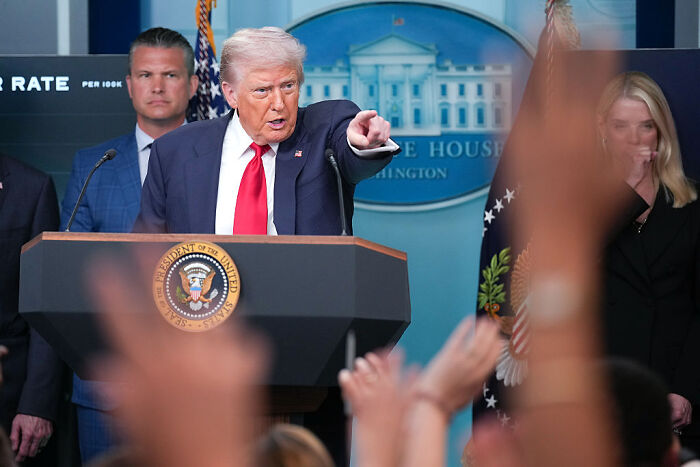 Former President Trump speaking at a White House briefing as experts warn about AI complexity and large language models issues.