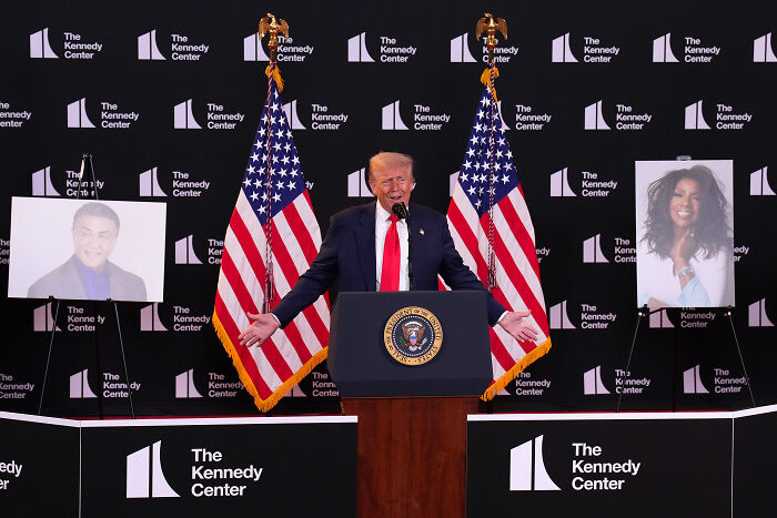 Former President Trump speaking at the Kennedy Center with American flags, related to LGBTQ+ icon Gloria Gaynor news.