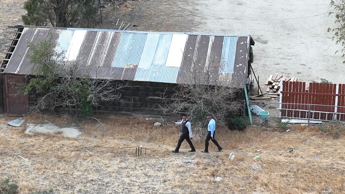 Two men walking near a weathered shed in dry grass, related to Emmanuel Haro&rsquo;s dad confession report.
