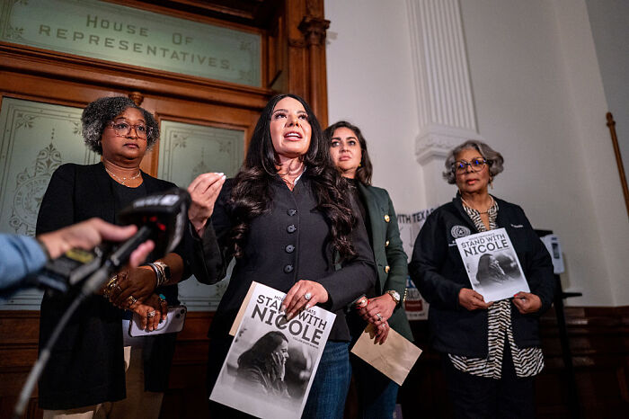 Women holding Stand With Nicole flyers at House of Representatives, discussing Texas GOP partisan map and redistricting plan.