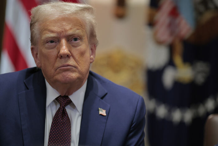 Former President Donald Trump in a suit, with American flag lapel pin, during a meeting in Washington D.C.