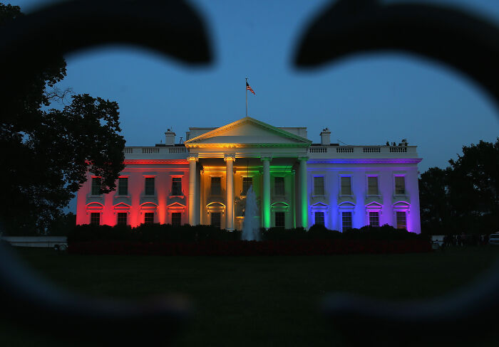 The White House lit in rainbow colors at night, symbolizing same-sex marriage and legal battle issues.