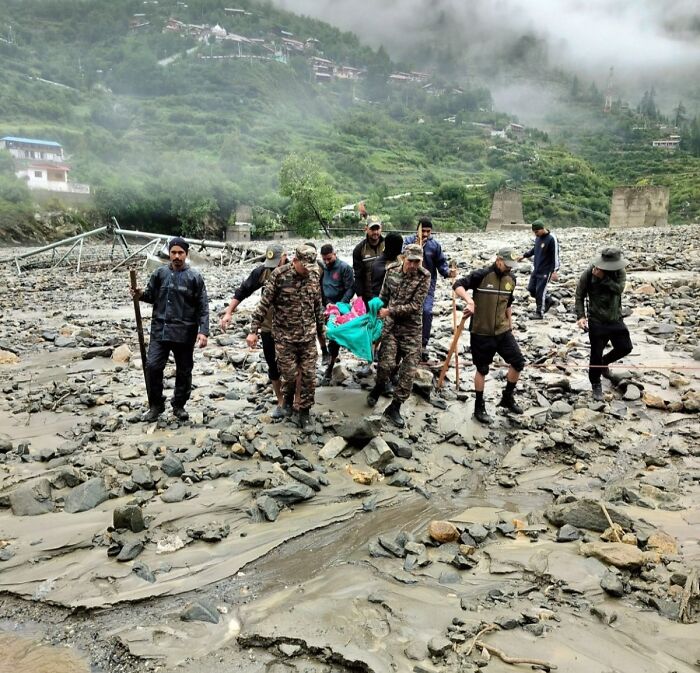 Rescue team carries victim through rocky, flood-damaged area after severe flash floods swept through entire town.