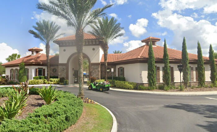 Modern residential community entrance with palm trees and clear sky, symbolizing the 9-year-old girl&rsquo;s courageous move story.