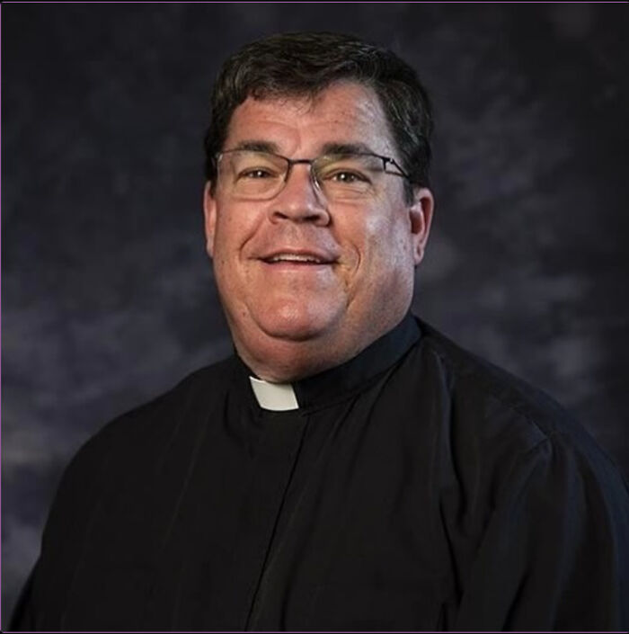 Man wearing glasses and a black clerical shirt with white collar, representing Alabama priest accused of secret romance.