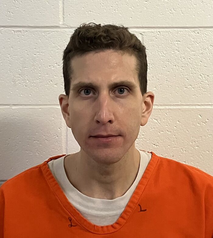 Male inmate in an orange prison uniform, photographed against a white cinder block wall, related to prison harassment campaign.