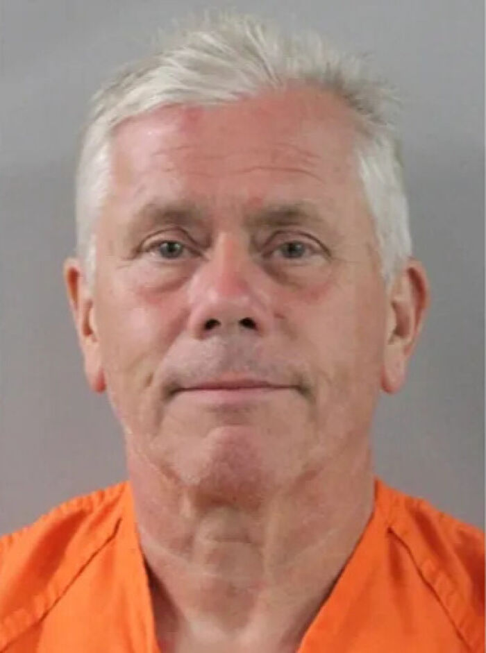 Mugshot of an older man with white hair in an orange prison jumpsuit related to grandpa drowning attempt case.