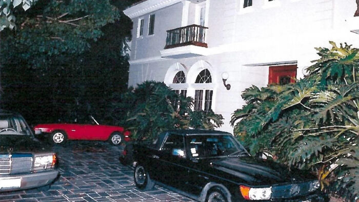 Driveway view of a mansion with parked cars, related to Erik Menendez denied parole case after slaying his parents.