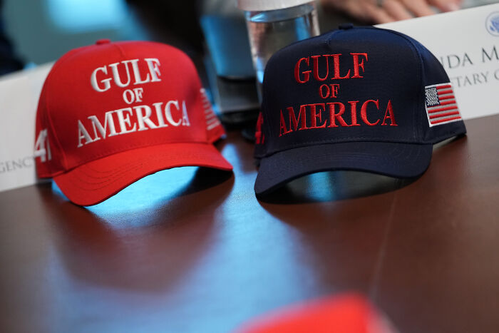 Two hats on a table with Gulf of America text, highlighting tensions affecting press freedom and journalists' safety.