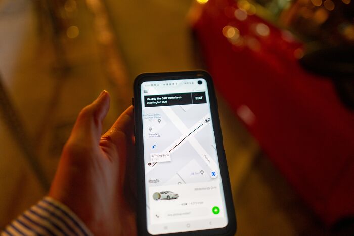 Person holding smartphone displaying ride app with map, highlighting Uber&rsquo;s alleged driver screening failures.
