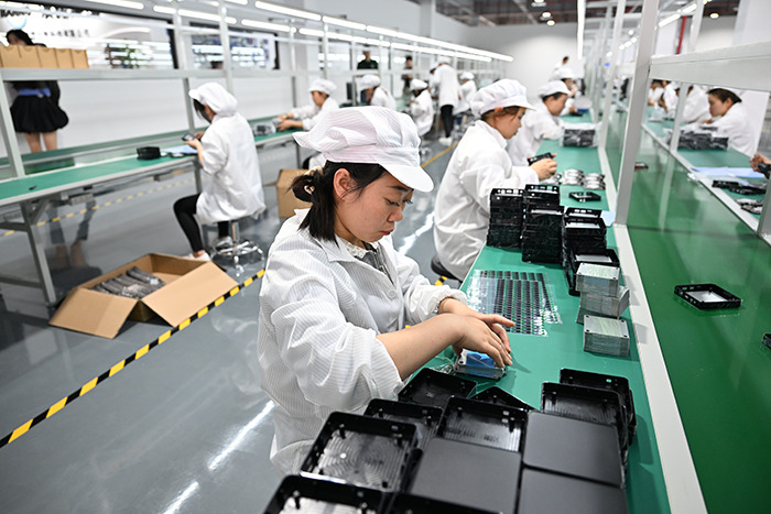 Factory workers assembling electronic components in a manufacturing facility, illustrating shifts in the global order and BRICS economic influence.