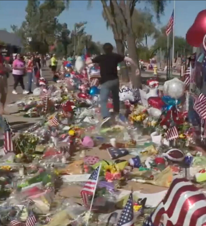 Teen wearing shirt resembling accused Charlie Kirk shooter stomps on memorial covered with American flags and flowers.