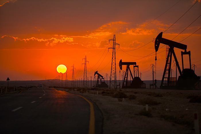 Sunset over an oil field with pumpjacks and power lines representing Brics dollar impact on the shifting global order.
