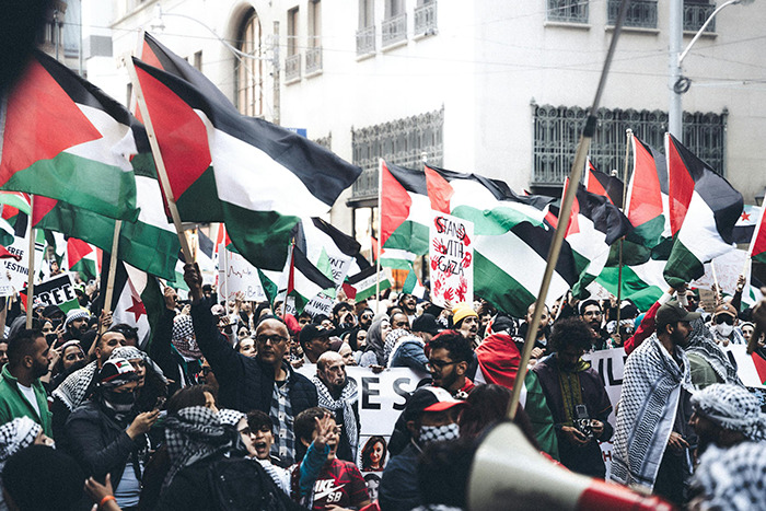 Crowd waving Palestinian flags during a street protest symbolizing shifting global order and BRICS-dollar geopolitical dynamics.