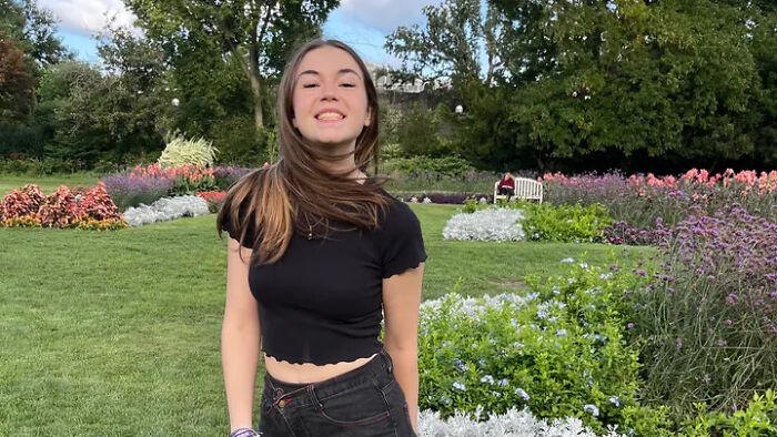 College student posing in a garden, representing smart brave strong woman facing harassment tragedy.