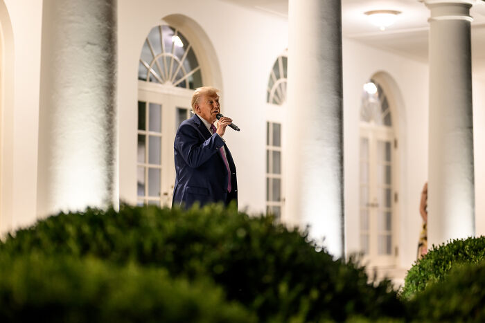 Donald Trump speaking at an outdoor event near White House pillars, related to Newsom slamming Rose Garden Club nickname.