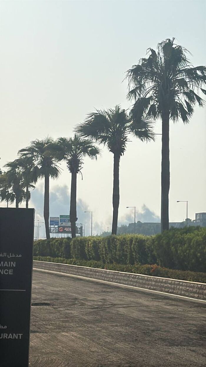 Smoke rising over Doha city skyline with palm trees lining the road during Israel attack on top Hamas leaders.