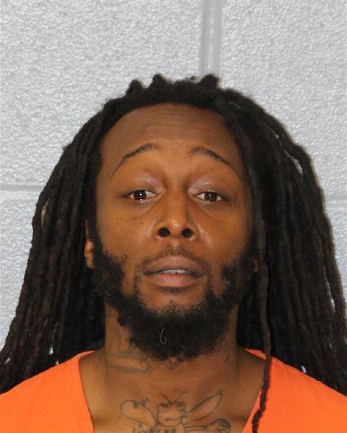 Mugshot of man with dreadlocks in an orange shirt related to GoFundMe pulling fundraising pages for ex-con accused of killing refugee.
