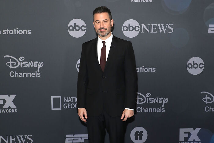 Jimmy Kimmel in a black suit and tie posing at a media event amid Disney and ABC News logos, related to Trump comments on Kirk murder.