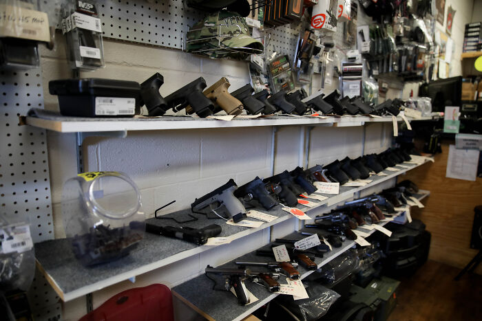 Shelves filled with various firearms and handgun accessories in a gun store amid possible firearm ban discussions.