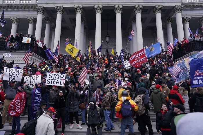 Crowd of protesters with flags and signs on courthouse steps highlighting America&rsquo;s escalating political violence concerns.
