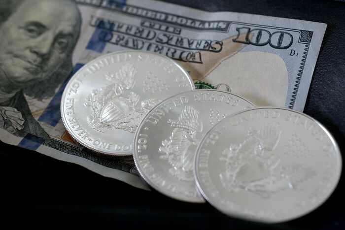 Silver coins and a hundred-dollar bill representing U.S. currency linked to slain activist Charlie Kirk GOP proposal.