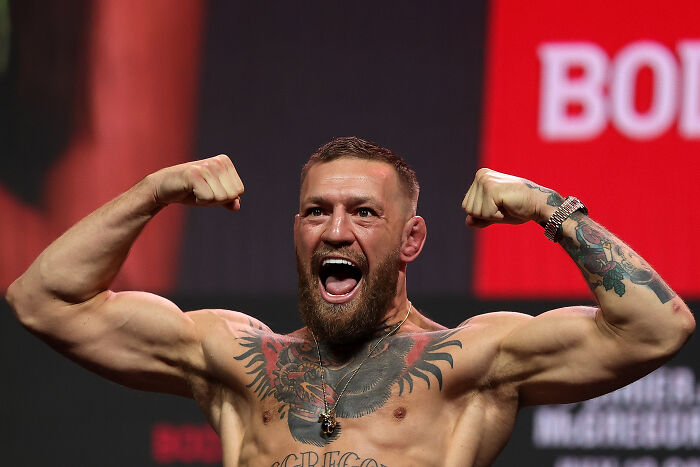 Conor McGregor flexing muscles and shouting on stage amid Irish presidency bid challenges and plea for support.