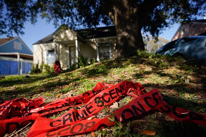 Red crime scene tape lying on grass near a house in Houston after an 11-year-old boy was fatally shot.