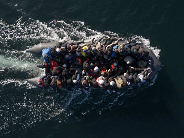 Overcrowded inflatable boat carrying migrants at sea, highlighting Europe's immigration challenges and ongoing crisis.