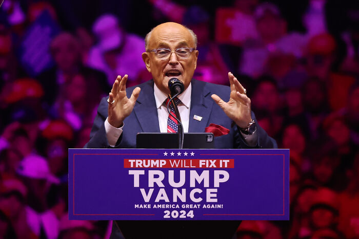 Rudy Giuliani speaking at a 2024 Trump Vance event, poised to receive Presidential Medal of Freedom award.