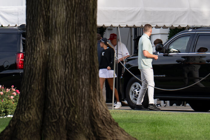 People near black SUVs outside a tent, illustrating social media impact on Donald Trump&rsquo;s public presence.