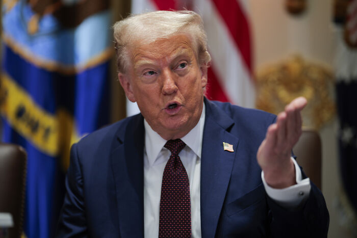 Former President speaking during a meeting with US flags in the background, related to firearm ban discussions.