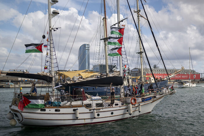 Sailboat with multiple Palestinian flags on Gaza flotilla, amid officials denying drone strike claims after reported attack.