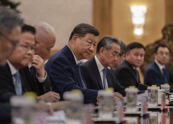 Xi Jinping leading a formal meeting, illustrating key figures linked to claims of conspiracy against the U.S. in geopolitical discussions.