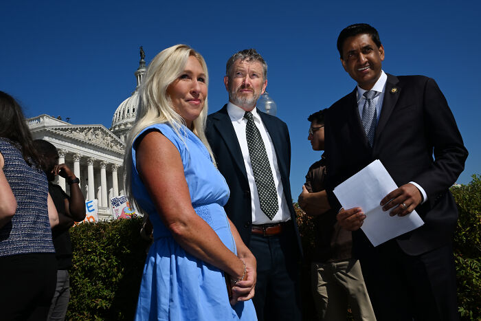 Epstein victims rally attendees stand near Capitol on a sunny day during a controversial jet flyover disruption.